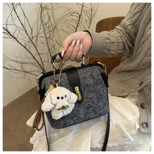 Detail of tweed doctors bag with golden lock, leather handle, and plush puppy charm