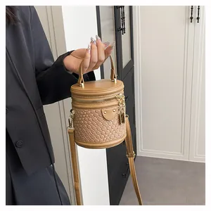 Detail der geflochtenen Eimertasche mit Tragegriff und goldenem Schloss in Karamell