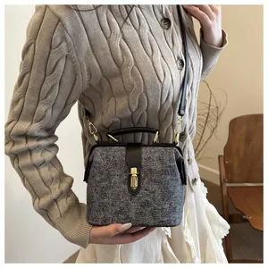Close-up of grey tweed doctor bag with leather trim held by a model in a beige sweater
