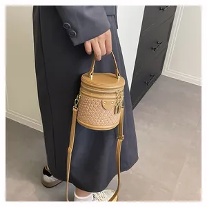 Detailansicht einer braunen geflochtenen Eimertasche mit Metallreißverschluss und Goldkette