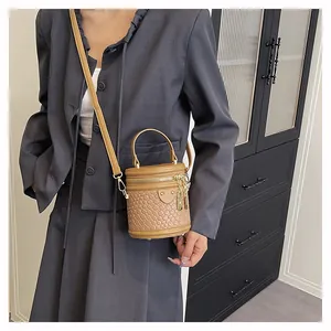 Detailansicht einer braunen geflochtenen Eimertasche mit Schloss und Schultergurt