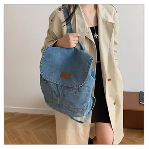 Close-up of denim backpack featuring vintage metal buttons and brown leather logo patch