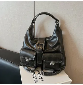 Detail of a black leather tote featuring retro buckle pockets and high-quality textures
