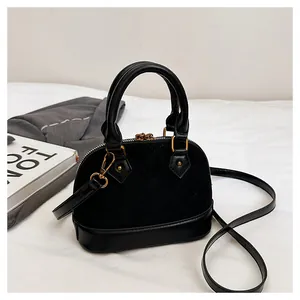 Détail macro d'un sac à main matelassé noir avec finitions dorées et texture suède
