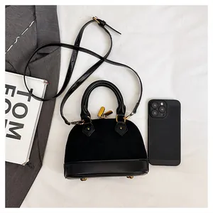 Gros plan sur un sac coquille matelassé avec fermetures dorées et téléphone de mesure