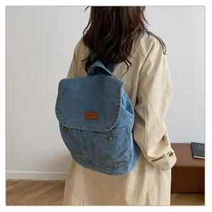 Detailed view of the blue denim backpack featuring metal buckles and a brown label patch