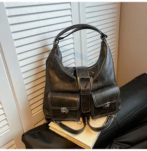 Close-up of black retro hobo bag with contrast stitching and decorative front pockets