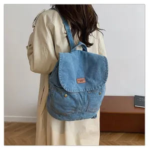 Detail shot of blue denim backpack with brown leather patch and dual snap-button pockets
