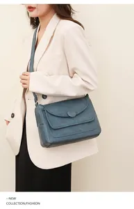 Modella che indossa borsa a tracolla in pelle PU blu scuro con fibbia rotonda