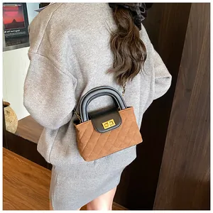 Detailed close-up of brown quilted suede bag with black leather handle and gold lock