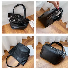 Detail view of large black leather tote bag with silver rivet studs and dual shoulder straps