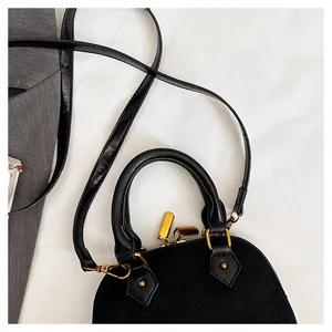 Détail du sac coquillage noir mat avec texture matelassée et fermeture éclair dorée élégante