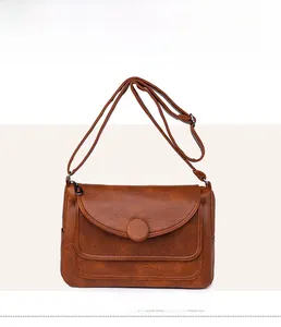 Dettaglio borsa marrone in pelle martellata con patta a semicerchio e fibbia ad anello