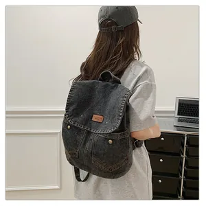 Detail of grey denim backpack with brown leather patch and vintage metal buckles