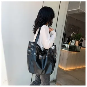 Detailed view of large black tote bag with silver studs on textured leather strap