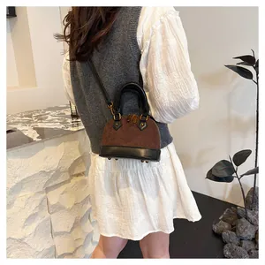 Détail d'un sac à main bicolore marron et noir porté à l'épaule avec des finitions dorées