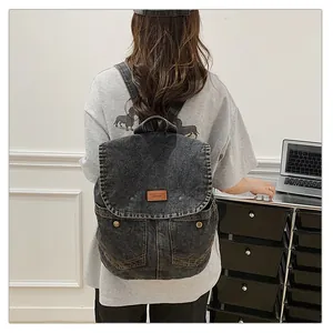 Detail of dark denim backpack featuring retro pockets and a premium leather brand patch