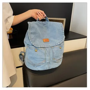 Close-up of light blue denim backpack with brown leather patch and retro button pockets