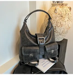 Macro view of distressed leather shoulder bag featuring white stitching and twin front pockets