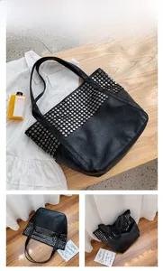 Detailed close-up of large black rivet tote bag with silver studs and soft leather texture