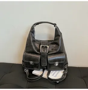 Detailed close-up of retro black leather tote with white contrast stitching and silver buckles