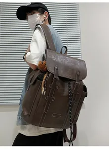 Seitenansicht des großen Vintage-Rucksacks in Dunkelbraun mit weißer Naht und Bärenanhänger