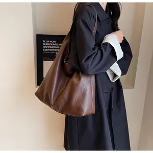 Detailed close-up of brown leather tote bag texture and wide shoulder strap