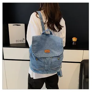 Detail of light blue denim backpack featuring vintage flap cover and leather patch design