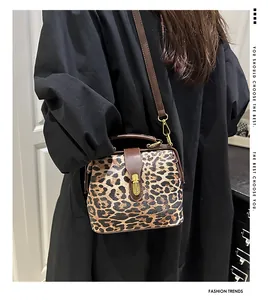Close-up of leopard print handbag with leather flap and golden metal clasp details