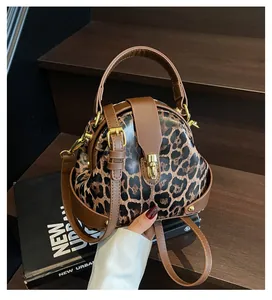 Detail of leopard print handbag featuring brown faux leather trim and gold metal buckle
