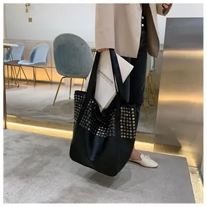 Close-up of black tote bag featuring silver rivet studs and a spacious shoulder design