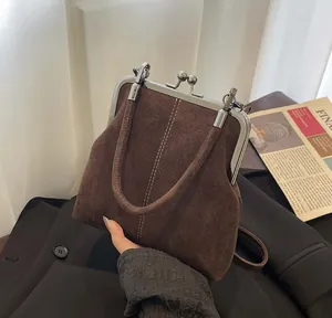 Detailed view of brown suede frame bag with vintage metal clasp and top handle texture