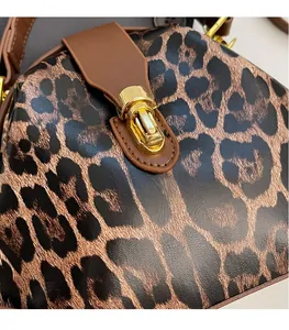 Detailed shot of leopard print shell bag featuring a gold rotating metal lock