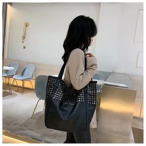 Detail of black rivet tote bag showing metallic silver studs and wide shoulder strap style