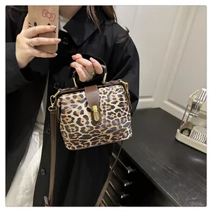 Detail of leopard print handbag with leather strap and golden metallic turn-lock