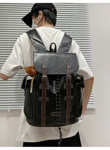 Detail eines schwarzen Vintage-Lederrucksacks mit braunen Riemen und Bärenanhänger