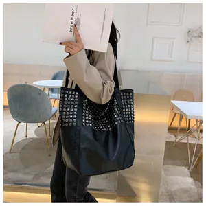 Detailed view of silver metallic studs on black leather tote bag with punk style accents
