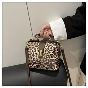Detailed shot of leopard print handbag featuring gold metallic twist lock and leather handle