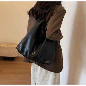 Side view of large black leather hobo bag on shoulder showing matte texture and slouchy fit
