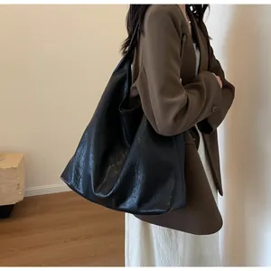 Minimalist large black leather tote bag with soft pleated texture on a female model