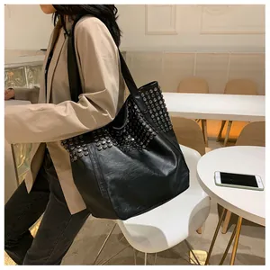 Detail of black leather tote bag featuring multiple rows of silver studs on the side