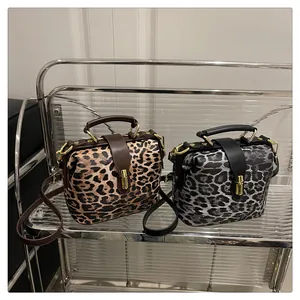 Detail view of leopard print crossbody bags in brown and grey displayed on a rack