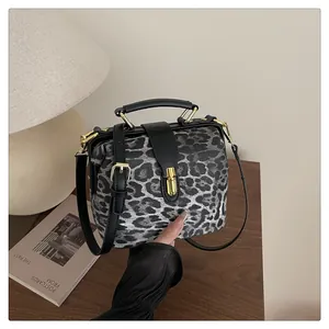 Close-up of leopard print fabric texture with black leather flap and gold metal clasp