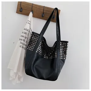 Close-up of black rivet tote bag showing metallic studs and soft leather texture