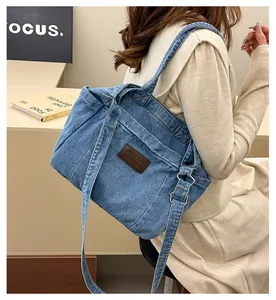 Close-up of light blue denim tote bag with brown leather label and adjustable strap