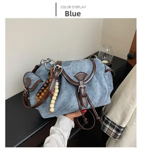 Close-up of blue denim bucket bag featuring brown leather strap and wooden bead charm