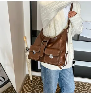 Detailed view of brown leather messenger bag featuring silver buckles and front pockets
