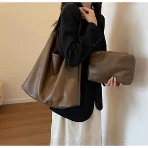 Λεπτομέρεια καφέ δερμάτινης τσάντας tote με φυσική υφή και ασορτί τσαντάκι clutch