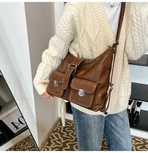 Detail of brown vintage crossbody bag with dual front pockets and silver metal buckles