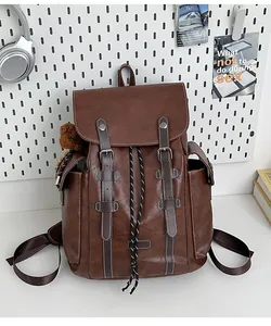 Detailansicht brauner Vintage-Lederrucksack mit Metallschnallen und Plüschbär-Anhänger